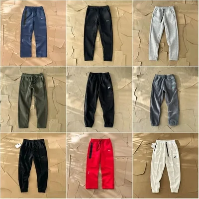 Nine pairs of joggers in grey, black, navy and red, photographed flat