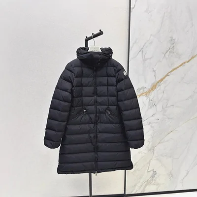 A long black quilted down coat on a hanger against a pale wall